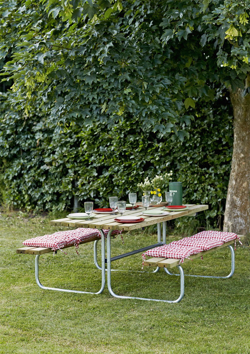 Picnicbord i haven med bænke og rødternet puder