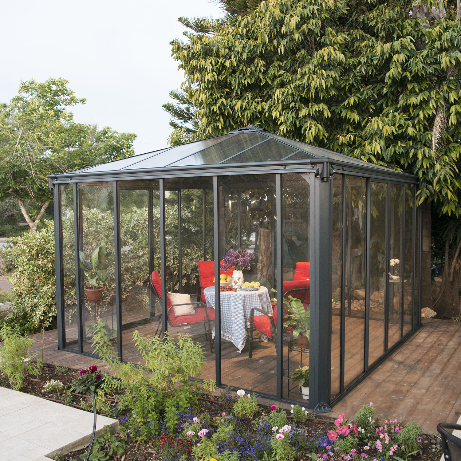 Elegant havestue i glas med terrasse Moderne glas havestue med møbler på træterrasse