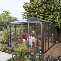 Elegant havestue i glas med terrasse Moderne glas havestue med møbler på træterrasse