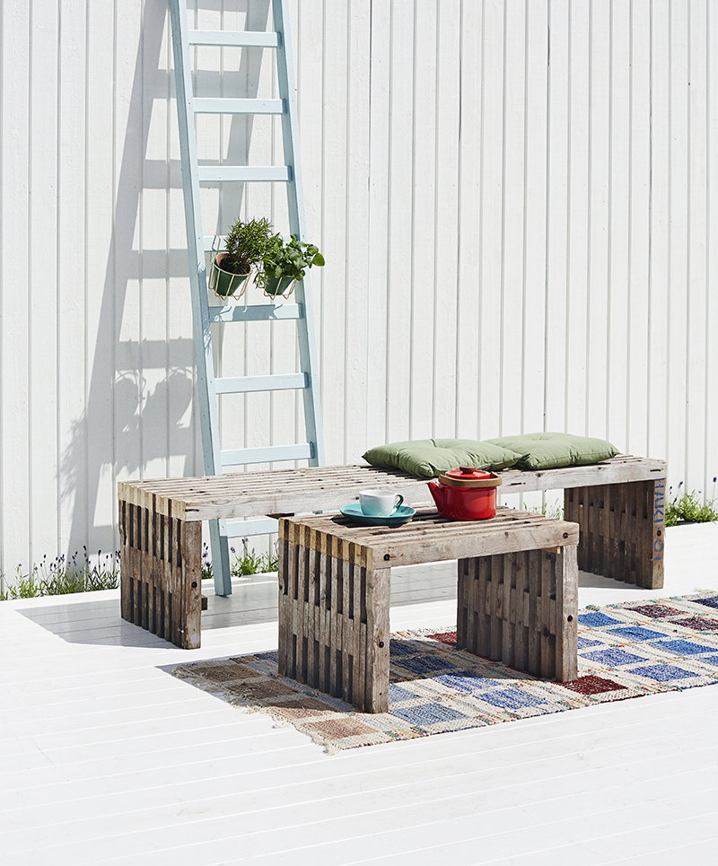 Udendørs pallebord og bænk på terrasse Rustikt pallebord og bænk med puder på hvid terrasse