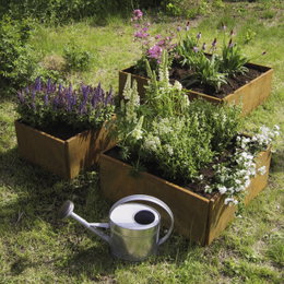 Blomstrende højbede i cortenstål med vandkande foran