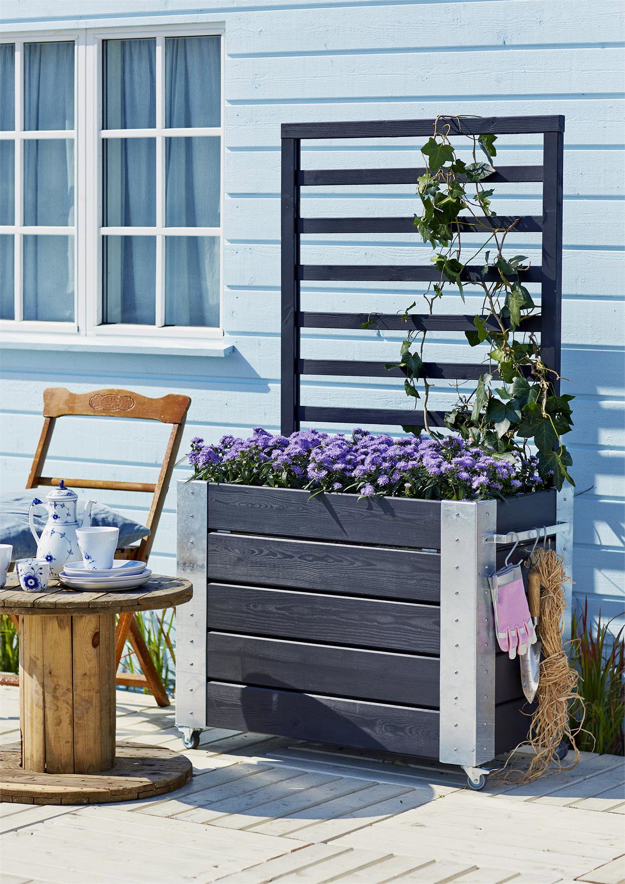 Høj blomsterkasse på hjul til terrasse Sort blomsterkasse på hjul med lilla blomster