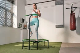 Salta Trampolin Fitness med håndtag, grøn – Salta mini trampolin til hjemmefitness Kvinde træner på Salta Trampolin Fitness med håndtag i grøn, mini trampolin til cardio og styrketræning hjemme