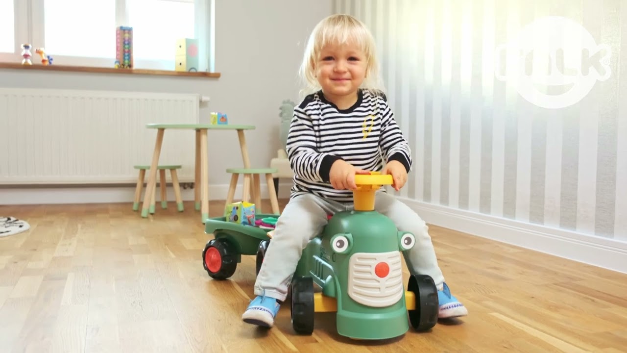 Barn leger på Maurice gå-traktor fra FALK, koralfarvet rød model med retningsbestemt rat, horn, lydnøgle og ergonomisk gåstøttebar – stimulerer fin- og grovmotorik